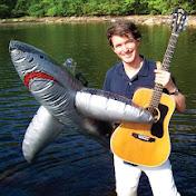Man holding a guitar and blow up shark