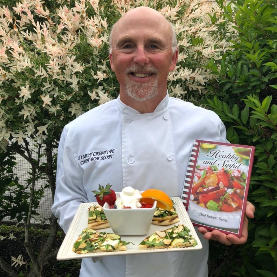 Chef Scott holding a platter of food and his cookbook