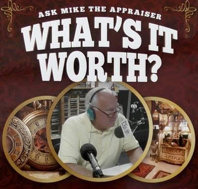 A man sitting at a desk with a microphone and various antiques around him.