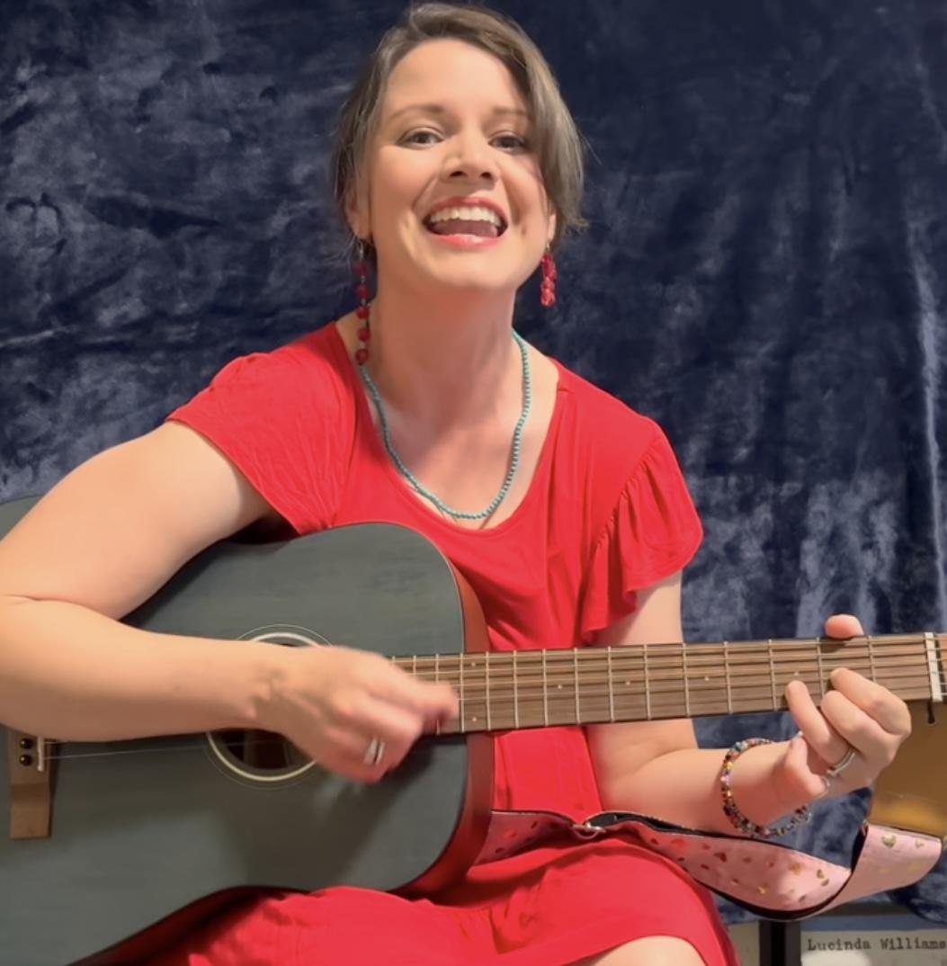 Woman in red dress playing guitar